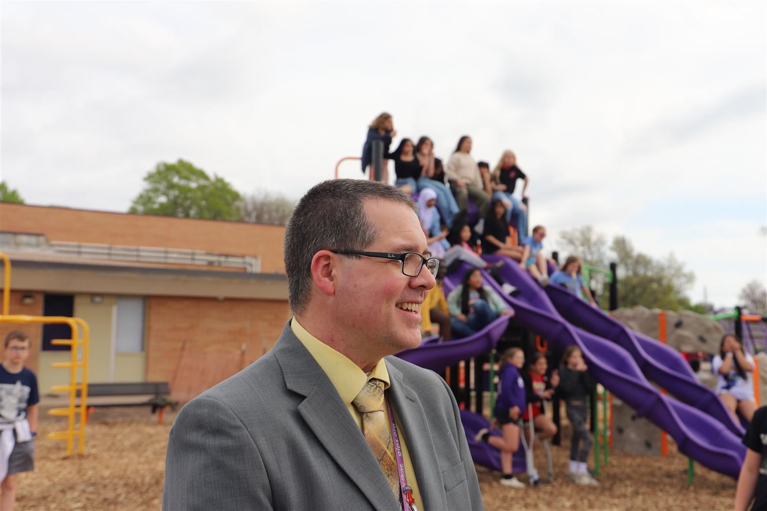 Mr. Balcom smiling by the Newell Playground with students.